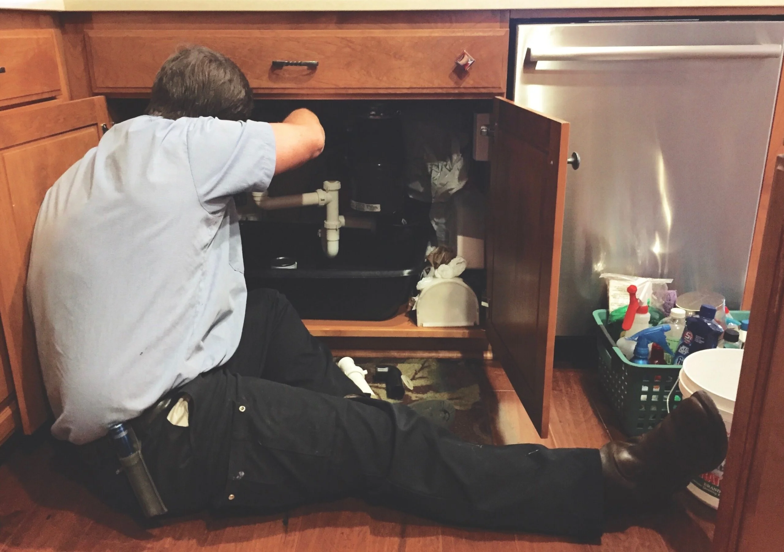 Technician repairing a kitchen garbage disposal.